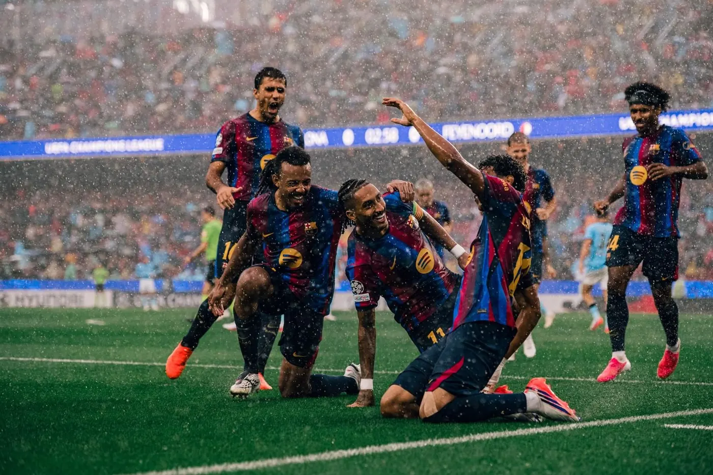 Barcelona players celebrate a Champions League goal against Feyenoord in heavy rain
