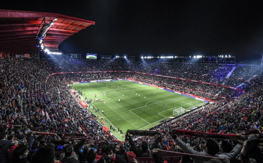 A packed La Liga stadium under floodlights at night
